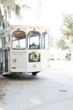 a white bus is parked on the side of the road with trees in the background