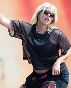 a woman in black shirt and shorts holding a tennis racquet on top of her head