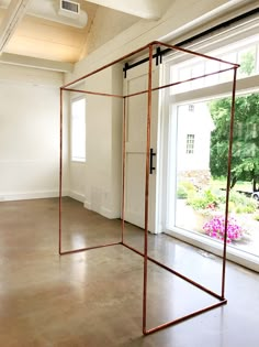 an empty room with two large windows and a metal frame on the floor in front of it