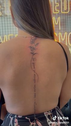 the back of a woman's neck with a tattoo on her left shoulder and flowers