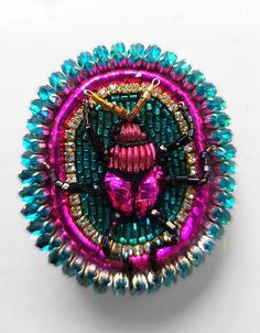 a colorful brooch with an insect on it's center surrounded by smaller beads