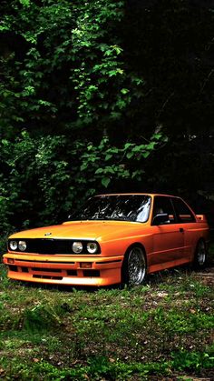 an orange car parked in front of some trees