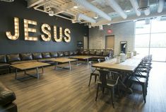 a large room with couches, tables and lights on the wall that read jesus