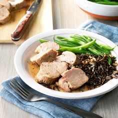 a white plate topped with meat, rice and green beans next to a bowl of broccoli