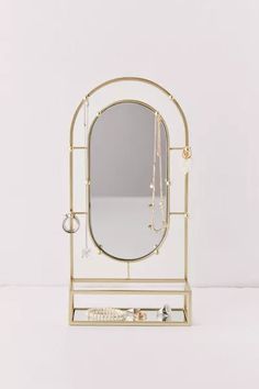 a mirror and jewelry stand on a white surface