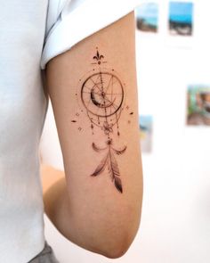 a woman's arm with a tattoo that has a compass and feathers on it