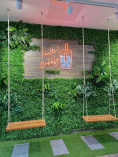 two wooden swings hanging from the side of a green wall with plants growing on it