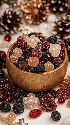 a wooden bowl filled with gummy bears next to pine cones and other christmas decorations