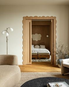 a living room with a couch, chair and bookcase in the doorway to a bedroom