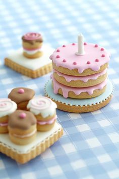 there is a small pink cake and cookies on top of each other, with one candle in the middle