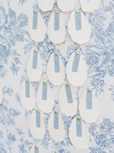 several pieces of paper with tags attached to them on a blue and white floral wallpaper