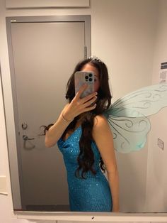 a woman taking a selfie in front of a mirror with a butterfly wings on it