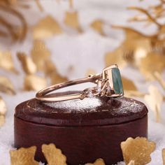 two wedding rings sitting on top of a wooden box in the snow with gold leaves around them