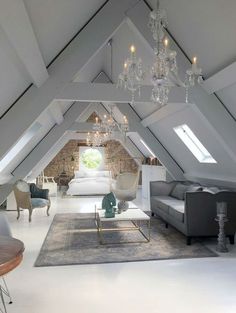 an attic living room with couches and chandelier