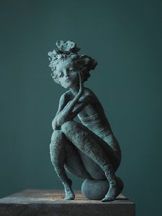 a sculpture of a woman sitting on top of a table