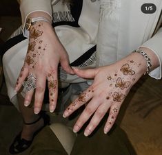 two hands with henna designs on them and one hand holding the other's wrist