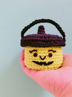 a small crocheted basket with a smiling face on it's head is held in someone's hand