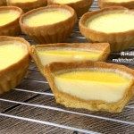 several mini cheesecakes on a cooling rack with one cut in half to show the inside