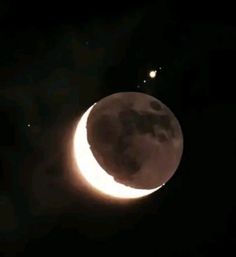 the moon is lit up in the dark night sky with two small stars above it