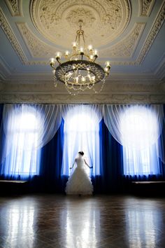 the bride is standing in front of two blue drapes and a chandelier