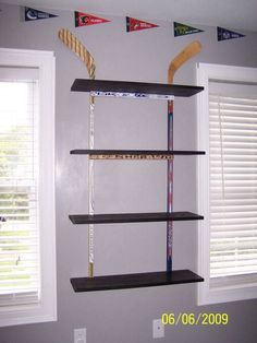 an empty room with three shelves and two windows in the corner, one shelf is filled with items