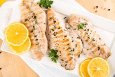 two fish fillets on a plate with lemons and parsley