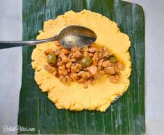 a spoon with some food in it sitting on a green plate next to a banana leaf