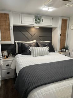 a bedroom with white and gray bedding, black and white pillows, and wooden headboard