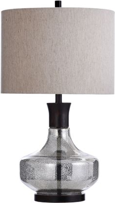 a glass table lamp with a beige shade