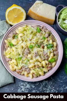 cabbage sausage pasta in a bowl with bread, lettuce and lemon wedges