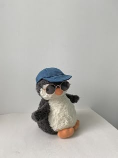 a small stuffed penguin wearing sunglasses and a blue hat sitting on top of a table