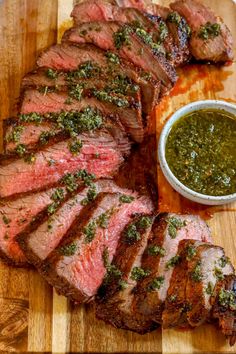 sliced steak on a cutting board with sauce and green pepper sprinkled on top