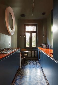 a kitchen with an orange counter top and blue cabinetry, along with a patterned tile floor