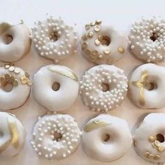 there are many donuts with white frosting and gold decorations