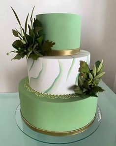 a three tiered green and white cake with succulents on the side