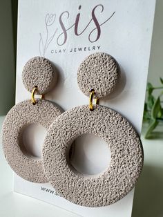 two circular stone earrings on top of a card with the word siss written below it