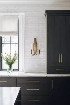 a kitchen with black cabinets and gold handles