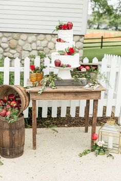 a table topped with a white cake covered in strawberries next to a wooden barrel