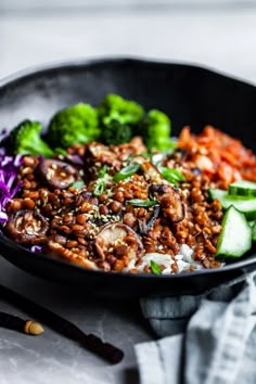 a black bowl filled with meat and vegetables