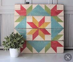 a potted plant sitting on top of a table next to a wooden wall hanging