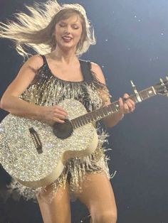 taylor swift performing on stage with her guitar