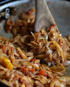 the food is being cooked in the skillet with a wooden spoon to stir it