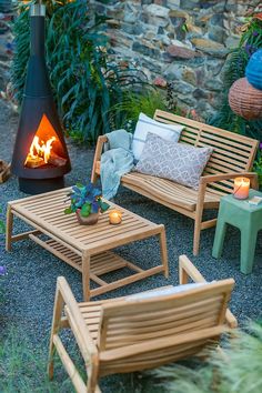 an outdoor seating area with wood furniture and a fire place in the back ground, surrounded by greenery