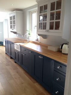 a large kitchen with wooden floors and white cupboards on the wall, along with an island