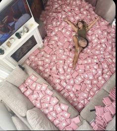 a woman laying on top of a bed covered in pink boxes