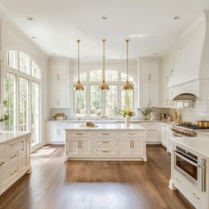 a large kitchen with white cabinets and wood floors