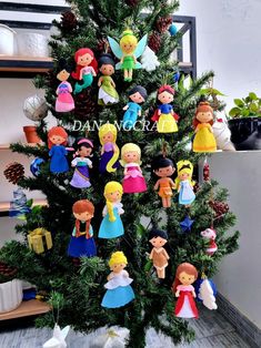 a small christmas tree with many dolls hanging from it