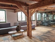 a living room filled with furniture and large windows next to a wall covered in wood planks