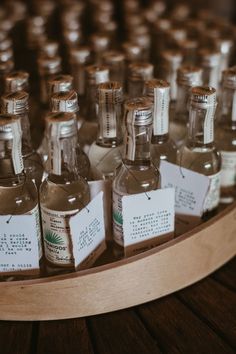 several small bottles with labels on them are lined up in a wooden display case,