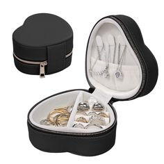 an open black jewelry box filled with lots of rings and necklaces on top of a white surface